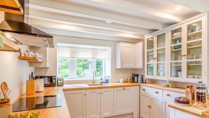 Une cuisine moderne avec des meubles blancs, un plan de travail en bois et une fenêtre qui laisse entrer la lumière naturelle.