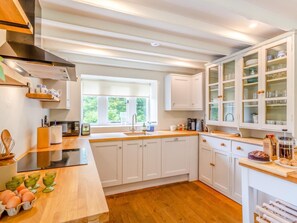 A modern kitchen with white cabinets, a wooden countertop, and a window providing natural light. - 4 Bed in Skipton (oc-92954) (Cracoe)