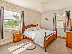 A bedroom with a wooden bed, bedside tables, a dresser, a window with curtains, and a view of greenery outside. - 4 Bed in Cowes (oc-92746) (Cowes)
