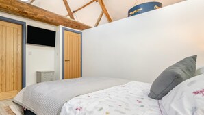 Quarto com cama, guarda-roupa, escrivaninha e luminária pendente.