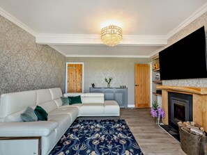 A living room with a white sofa, a blue patterned rug, a fireplace, and a television. - 3 Bed in Burnham-on-sea (oc-92964) (Brean)