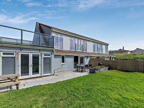 Un immeuble résidentiel de deux étages doté d’un patio, d’une clôture en bois et d’une cour arrière enherbée.