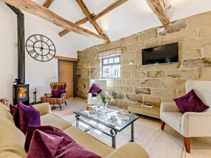 Ein gemütliches Wohnzimmer mit Steinwand, Kamin, großer Uhr und Fernseher.