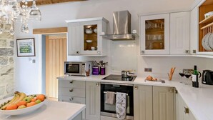 A modern kitchen with white cabinets, a built-in oven, a microwave, and a stainless steel range hood. - 2 Bed in Chop Gate (oc-93098) (Chop Gate)