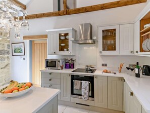Eine moderne Küche mit weißen Schränken, einem eingebauten Backofen, einer Mikrowelle und einer Edelstahl-Dunstabzugshaube.