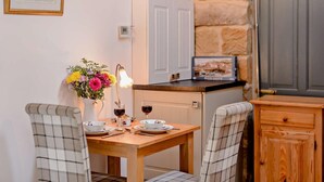 A cozy dining area with a wooden table set for two, a vase of flowers, and a lamp. - 1 Bed in Chop Gate (oc-93100) (Chop Gate)
