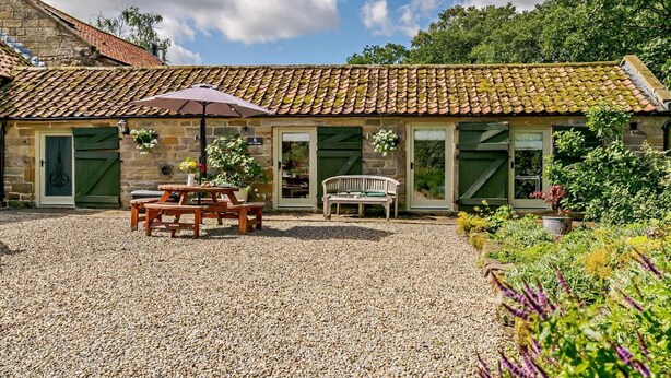 A stone building with a tiled roof, a gravel courtyard, wooden benches, and potted plants. - 1 Bed in Chop Gate (oc-93100) (Chop Gate)
