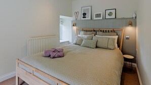 A bedroom with a bed, a radiator, a bedside table, and a wall-mounted shelf with pictures. - 1 Bed in Machynlleth (oc-92689) (Pennal)
