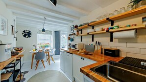 A modern kitchen with wooden shelves, a built-in oven, and a large window. - 1 Bed in Machynlleth (oc-92689) (Pennal)