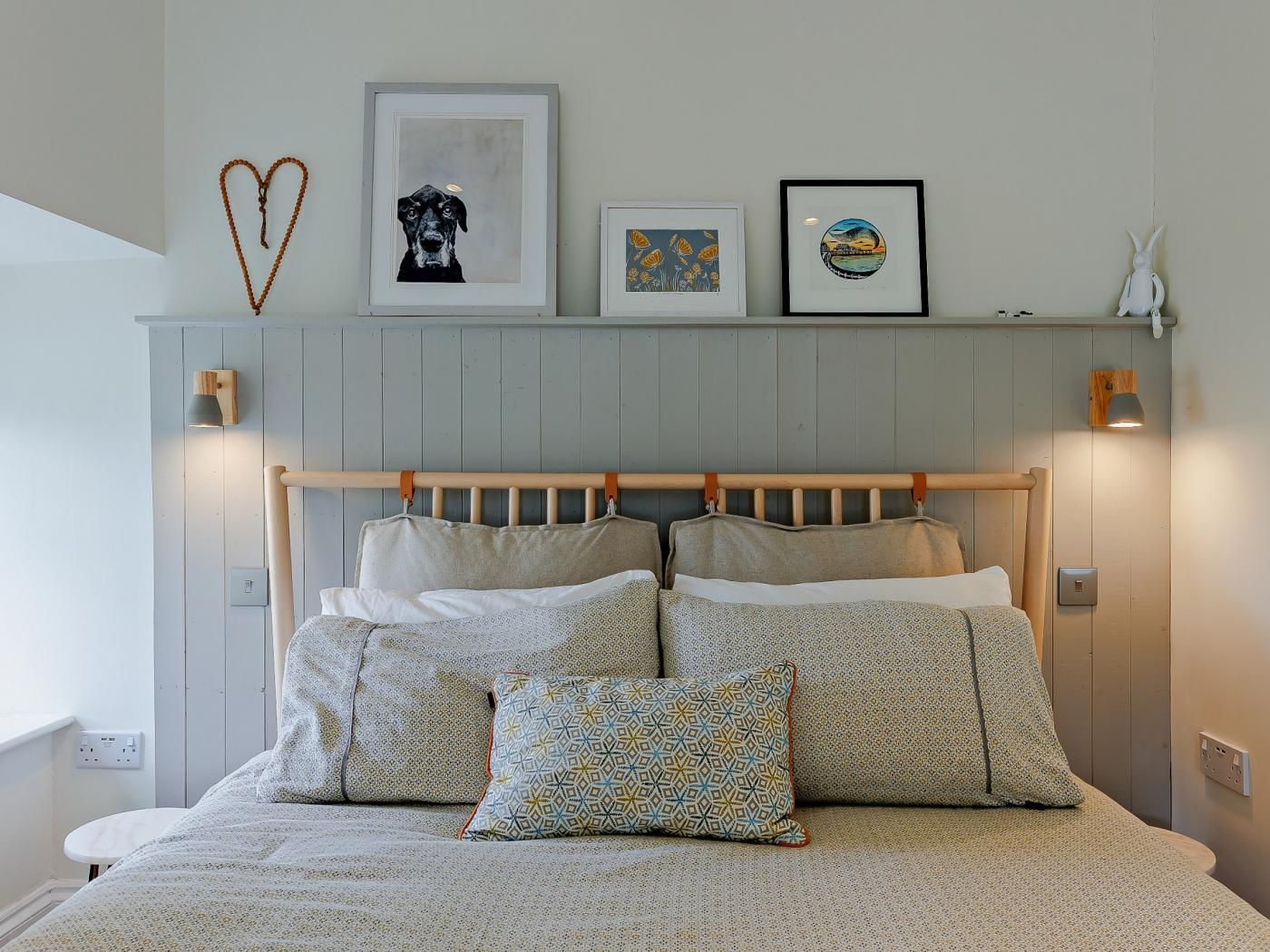 Een slaapkamer met een houten hoofdbord, meerdere kussens en wanddecoratie.