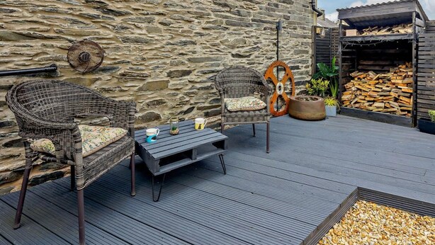 A stone wall, wicker chairs, a table, and a woodpile outside a building. - 1 Bed in Machynlleth (oc-92689) (Pennal)