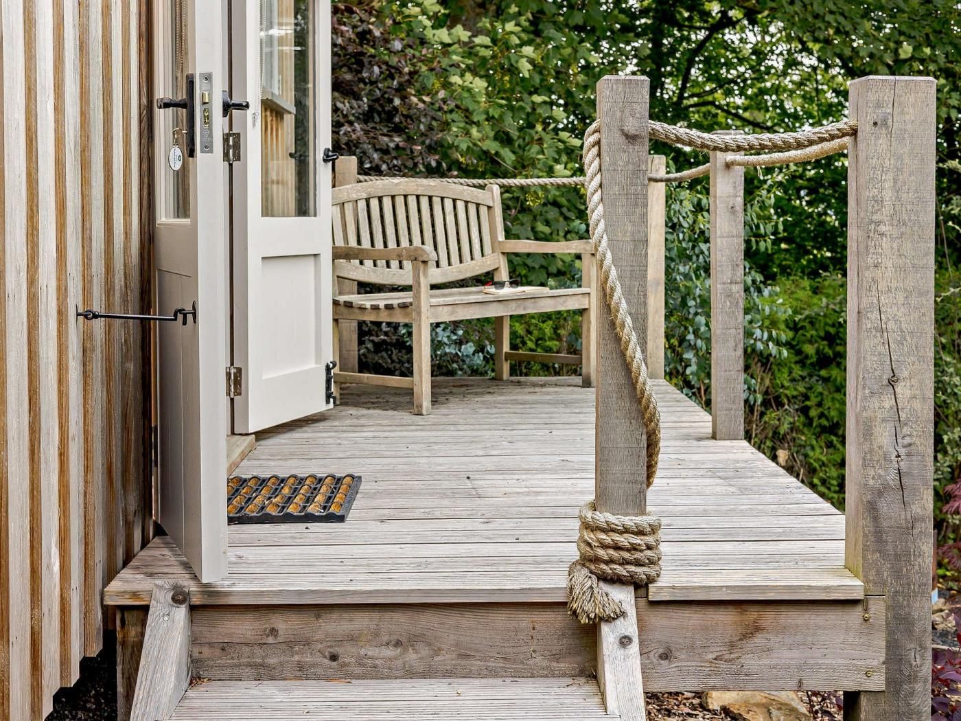 A wooden deck with a bench and a rope barrier.
