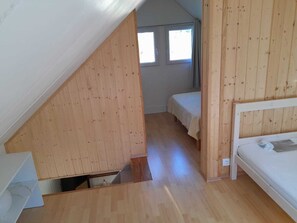 Une pièce avec un plafond en pente, des murs en bois, un lit et une fenêtre.