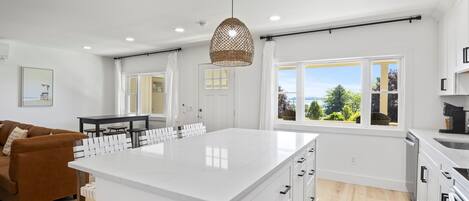 A spacious kitchen with a large island, white cabinetry, and a view through the windows.