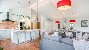 Eine moderne Küche mit Kochinsel, einem Essbereich mit einer Couch und einer roten Pendelleuchte.