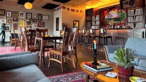 Un intérieur chaleureux avec des meubles en bois, un coin bar et diverses œuvres d’art.