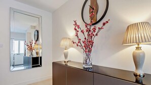 Un intérieur moderne avec un mur miroir, une console aux tons sombres et deux lampes.