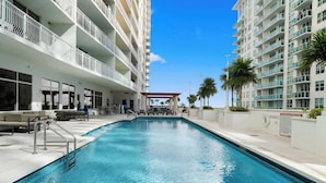 A swimming pool with a sun terrace, surrounded by multi-story buildings with balconies. - Luxury Brickell With City Views & Rooftop Pool (Miami)