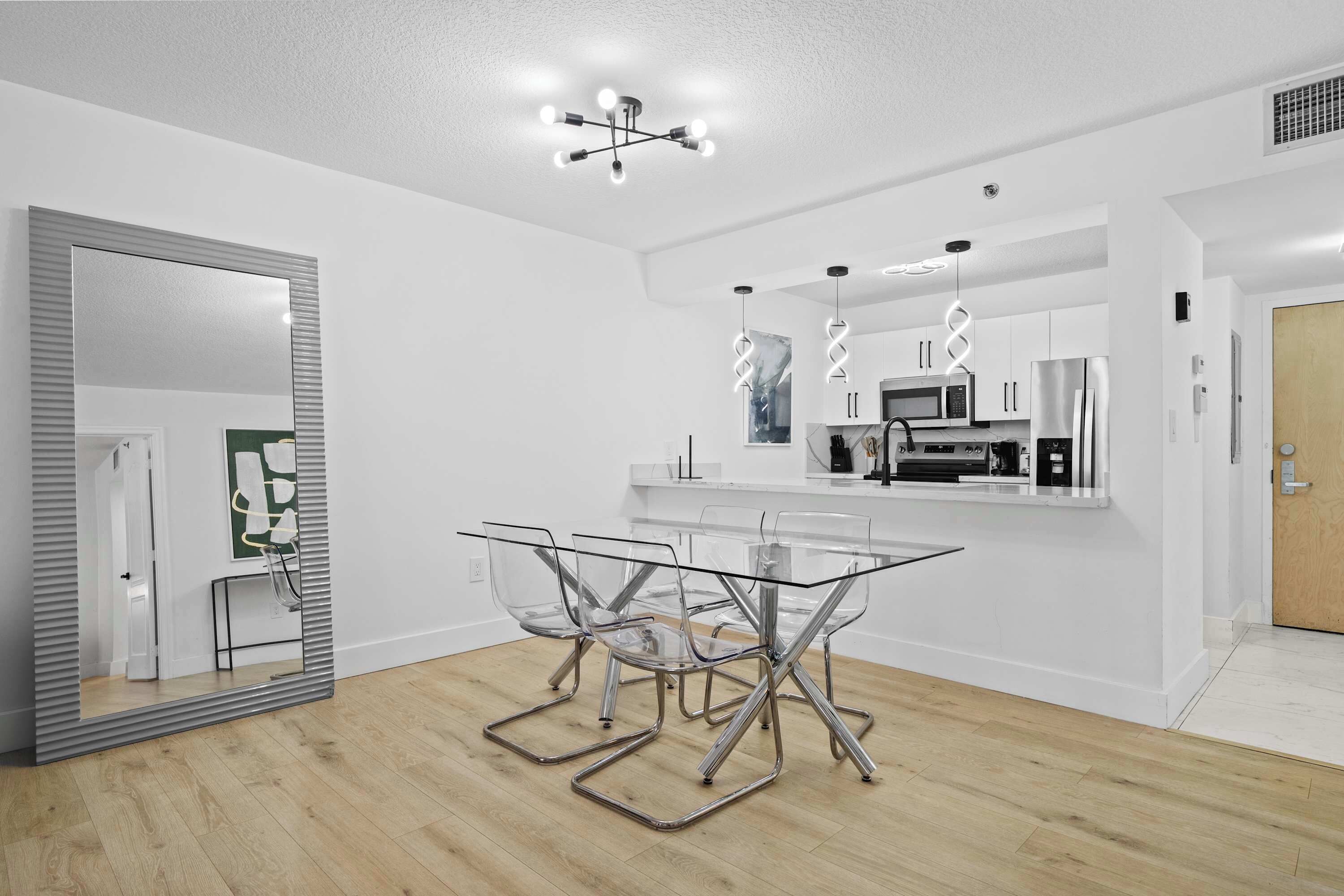 A modern kitchen with white cabinets, a stainless steel refrigerator, and a microwave.