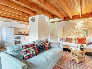 A cozy living area with a light blue sofa, a wicker side table, and a stone wall. - 3 Bed in Haverfordwest (oc-92675) (Solva)