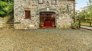 A stone building with a gravel driveway, a wooden gate, and a small garden area. - 3 Bed in Haverfordwest (oc-92675) (Solva)