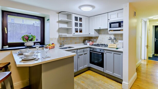 Une cuisine moderne avec des meubles blancs, un îlot central, un four à micro-ondes et un évier.