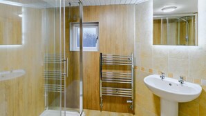 Une salle de bain moderne avec une douche à parois de verre, un porte-serviettes, un lavabo et un miroir.