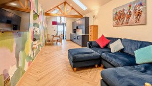 A spacious living area with a large sofa, a dining table, and a kitchen in the background. - 1 Bed in Lockerbie (oc-93110) (Lockerbie)