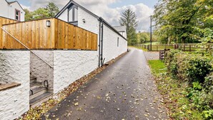 A rural road leading to a white building with a wooden fence, a clear sky, and trees in the background. - 1 Bed in Lockerbie (oc-93110) (Lockerbie)