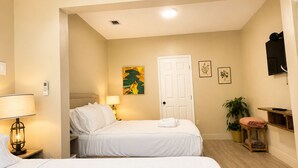A hotel room with two beds, a bedside table with a lamp, a door, and a small plant. - Design District suite with free parking, centrally located. (Miami)