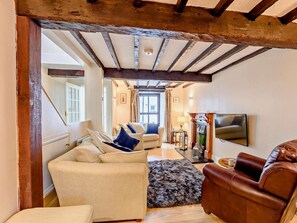 Ein Wohnzimmer mit Kamin, einem an der Wand befestigten Fernseher und einer Treppe zu einem anderen Raum.