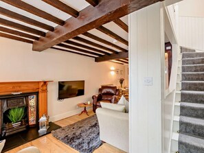 Ein Wohnzimmer mit Kamin, Fernseher, Sofa und Treppe.