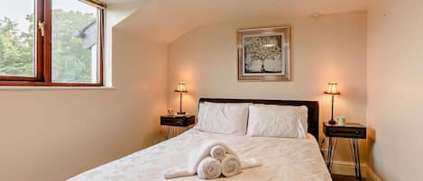 A bedroom with a bed, two bedside tables, a window, and a ceiling light.