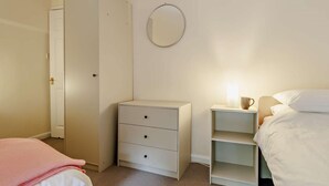 A bedroom with a bed, a dresser, a nightstand with a lamp, a wardrobe, and a mirror on the wall. - 3 Bed in Machynlleth (oc-93083) (Cwm-Llinau)