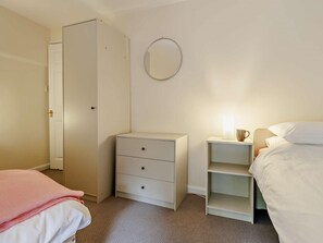 A bedroom with a bed, a dresser, a nightstand with a lamp, a wardrobe, and a mirror on the wall. - 3 Bed in Machynlleth (oc-93083) (Cwm-Llinau)
