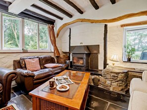 A cozy living room with a stone fireplace, leather sofa, and a coffee table with a newspaper. - 3 Bed in Machynlleth (oc-93083) (Cwm-Llinau)