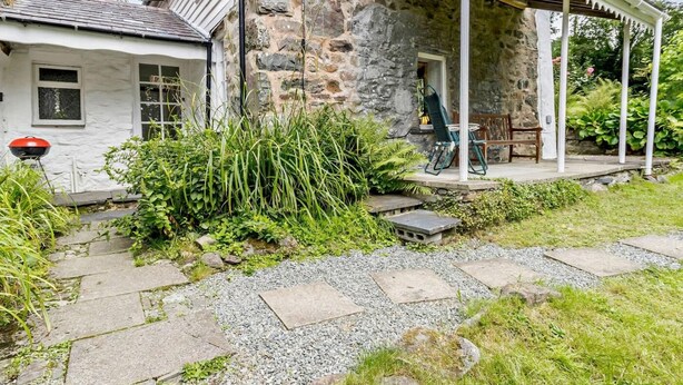 A stone house with a porch, a grill outside, and a garden path. - 3 Bed in Machynlleth (oc-93083) (Cwm-Llinau)