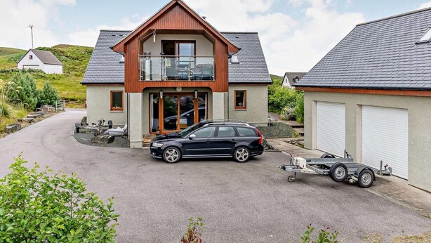 Ein zweistöckiges Haus mit Balkon, einem Auto und einem Anhänger.
