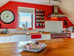 A kitchen with a red wall, a clock, a window, and a stove. - 3 Bed in Gairloch (oc-92714) (Badachro)