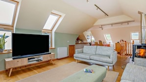 A spacious living room with a flat-screen TV, a sofa, a fireplace, and a dining area.