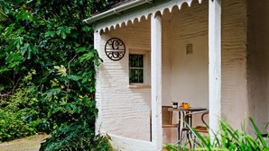 A white building with a porch, a circular sign, and a table with chairs. - 2 Bed in Machynlleth (oc-93079) (Cwm-Llinau)