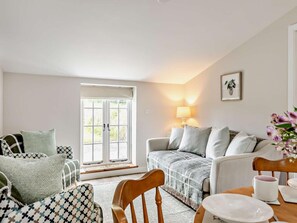 Ein gemütliches Wohnzimmer mit einer Couch, Sesseln, einem Esstisch und einem Fenster mit Blick.