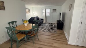 En kompakt opholdsstue med spiseplads, en sofa, et fjernsyn og et mønstret tæppe.