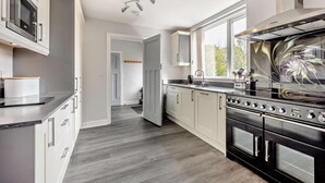 A modern kitchen with a large stove, cabinets, and a window. - 3 Bed in Keswick (oc-93202) (Keswick)