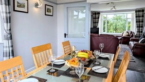 A dining area with a table set for four, a sofa, and a view of the outdoors. - 3 Bed in Keswick (oc-93202) (Keswick)