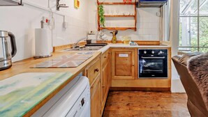 A compact kitchen with a dishwasher, oven, and a waste bin. - 1 Bed in Machynlleth (oc-93081) (Cwm-Llinau)