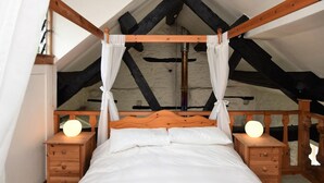 A bedroom with a four-poster bed, wooden nightstands, and a sloped ceiling with exposed beams. - 1 Bed in Machynlleth (oc-93081) (Cwm-Llinau)