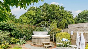 Ein Whirlpool, umgeben von einer Holzterrasse, einem kleinen Tisch mit Stühlen und einem Holzzaun.