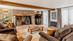 Ein Wohnzimmer mit Kamin, Sofas, einem Couchtisch und einem Fernseher.