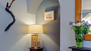 Ein Zimmer mit einer Lampe, einem gerahmten Bild und einer Vase mit Blumen.